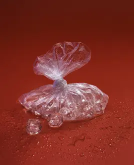 Live Still Life Photography Prints: Translucent plastic bag with ice cubes on a red surface