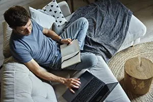 Man Working On Laptop Prints: Above view of man sitting on sofa and using laptop