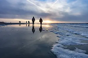 Evening Sun Germany Prints: Walkers at sunset on the beach
