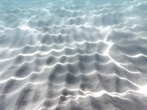 Light Reflection On Water Prints: Wave patterns and light reflections in the clear water over a sandy bottom