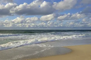 Cumulus Humilis Clouds Prints: Waves running out at the sandy beach