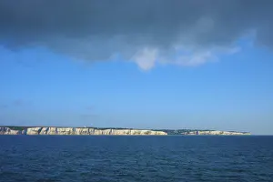 Chalk Cliff Coastline Prints: White cliffs under a dramatic sky with cloud formations over blue water
