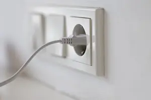 Energy Consumption Symbol Prints: White power plug in a socket on the wall