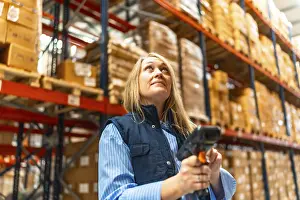 Warehouse Worker Prints: Woman worker scanning package with bar code reader in a distribution warehouse