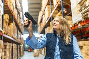 Distribution Warehouse Worker Prints: Woman worker scanning package with bar code reader in a distribution warehouse