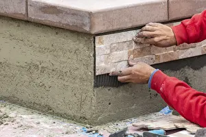Construction Site Worker Prints: Worker installing wall tile at construction site