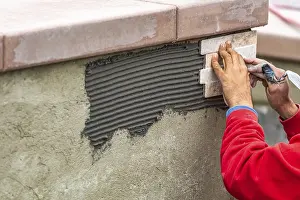 Construction Site Worker Prints: Worker installing wall tile at construction site