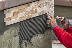 Construction Site Worker Prints: Worker installing wall tile at construction site