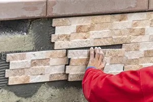 Construction Site Worker Prints: Worker installing wall tile at construction site