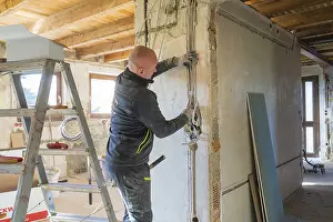 Construction Site Labourer Prints: A worker installs cables on a construction site
