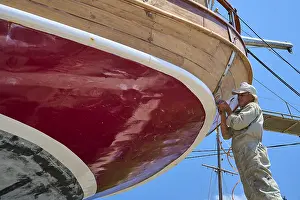 Prints of A worker is working on the red hull of a sailing ship, Patmos Marine, boatyard, Diakofti, Patmos, Dodecanese, Greek Islands, Greece Sport Prints: Patmos Marine Boatyard Print, Greek Islands