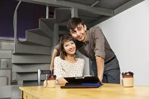 Young Couple Prints: Young couple with tablet computer sitting at the table