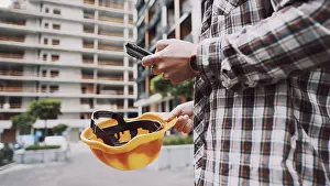 Construction Site Worker Prints: Young Engineer using smartphone on construction site