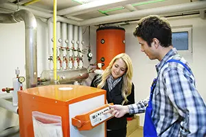Power Generation In Europe Prints: Young heating technician maintains a heating system