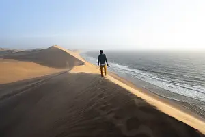 Barren Desert Landscape Prints: Young man with camera standing on a dune