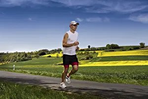 Fitness In Nature Prints: A young man jogging through the fields