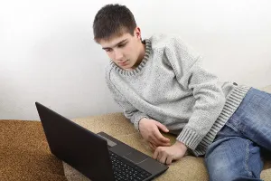 Young Man On Sofa Prints: Young man with notebook on sofa