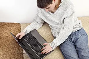 Young Man On Sofa Prints: Young man with notebook on sofa